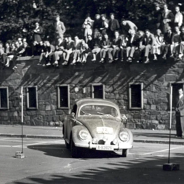 Eldre fotogfrafi av rallybil foran folkemengde